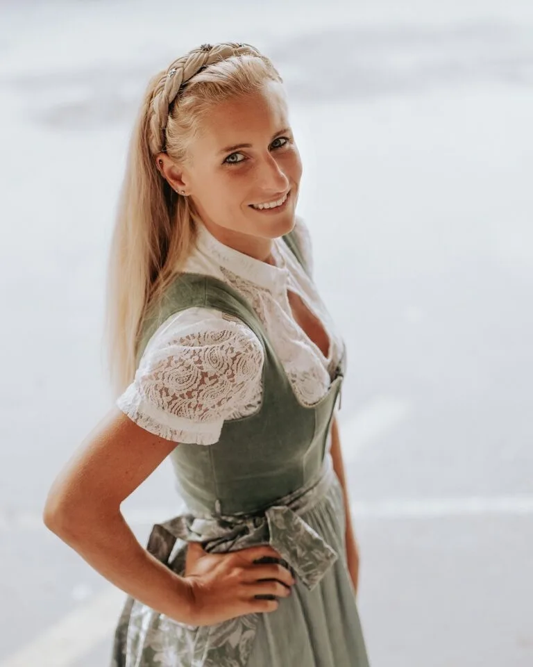 Lächelnde Frau in einem grünen Samt-Dirndl mit weißer Spitzenbluse